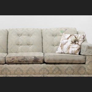 detail of mended couch showing camouflage patch and throw pillow