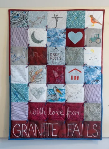 DSC06918 A quilt in dusty blues and burgundies that says "With Love from Granite Falls"