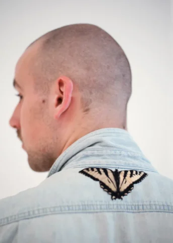 Alterations_Alterations-92_edit_layrs copy A person faces away from the camera, showing the swallowtail butterfly patch sewn onto their denim shirt.