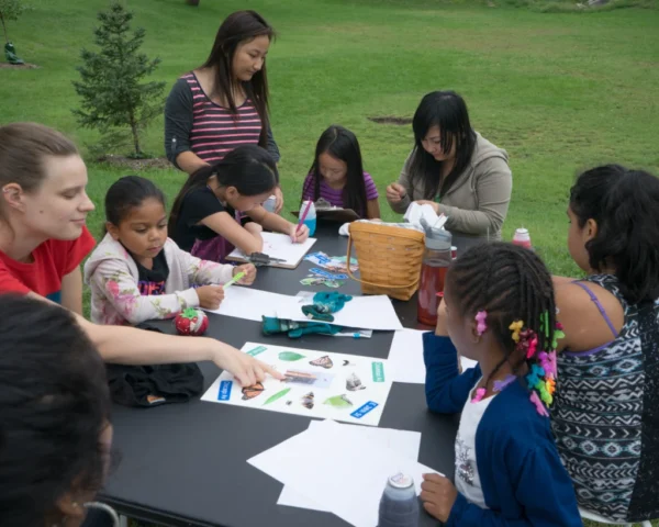 Amendments_DSC00945 copy Facilitator points at different fabric patch options while a diverse group of young people gathers around the table.