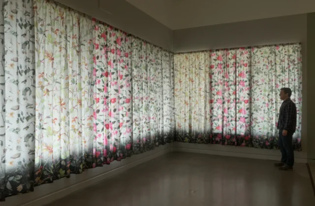 SLRogers_08269 Installation view of the roses curtains showing the scale of the installation, conveyed by a person looking at them.