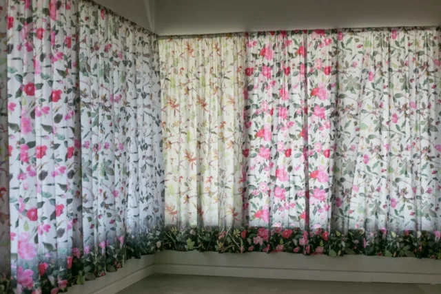SLRogers_5588_roses An L-shaped wall of windows is covered in fabric showing roses through each of the four seasons